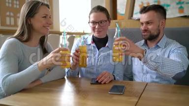 三个朋友坐在咖啡馆里，喝果汁，在交流中玩得开心